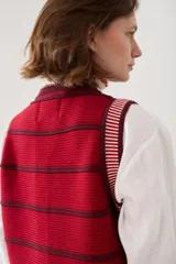 Chaleco tejido de punto sin mangas, con rayas horizontales azul marino y blancas, cierre frontal con botones y terminaciones en crochet rojo.