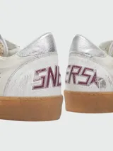 Zapatillas Golden Goose modelo Ball Star, color blanco con detalles en verde y plateado. Confeccionadas en cuero con efecto desgastado, presentan una estrella verde en el lateral, talón plateado y suela de goma color caramelo.