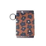 Billetera elástica de tela con estampado floral en tonos marrones, negros y azules. Incluye un anillo metálico para llavero.