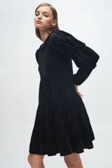 Vestido corto de terciopelo color cobre, con diseño de volados en capas, cuello redondo con detalle de volado y mangas largas con fruncidos.