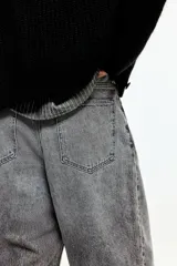 Jean de cinco bolsillos en denim de algodón rígido, de corte holgado con piernas redondeadas extraamplias, tiro bajo y cierre frontal.