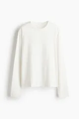 Remera de manga larga color blanco, confeccionada en punto de algodón suave, con cuello redondo y diseño básico de corte recto.
