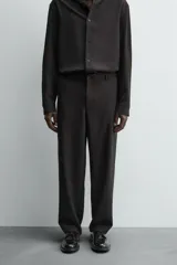 Pantalón de corte relaxed fit, con cintura ajustable, bolsillos delanteros y bolsillo trasero de plastrón. Presenta cierre frontal con cremallera y botón.