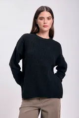 Buzo de tejido de punto negro, con cuello redondo y manga larga, de calce holgado.