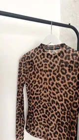 Top de microtul con estampado animal print de leopardo, cuello alto y mangas largas.