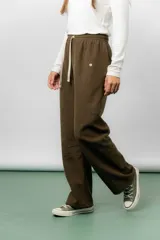 Pantalón de corte relajado y pierna recta, confeccionado en tejido tipo corderoy liviano. Presenta cintura elastizada con cordón ajustable y diseño de silueta amplia.