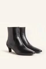 Botín blanco con estampado de piel de serpiente, punta fina y taco chupete. Cierre con cremallera en la parte trasera.