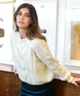 Sweater de lana merino color marfil, tejido a mano, con cuello redondo y detalles de punto trenzado y calados en V en el frente y las mangas.