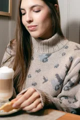 Polera de tejido de punto con cuello alto, diseño holgado y estampado jacquard con motivos geométricos y figuras en tonos beige, naranja y celeste.