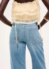 Pantalón de mezclilla de tiro medio con diseño acampanado estilo flare, trabillas para cinturón y clásico diseño de cinco bolsillos con cierre frontal de botón y cremallera.