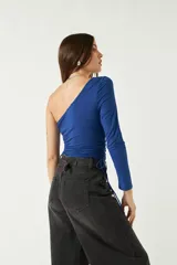 Top asimétrico de una sola manga larga, color azul, con jaretas ajustables en ambos laterales del torso que permiten regular el largo de la prenda.