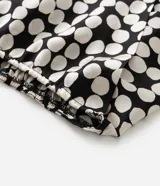 Blusa de crepé satinado con estampado de lunares, escote en V cruzado y mangas cortas tipo campana.