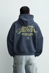 Sudadera tipo hoodie de corte relajado en color azul oscuro con efecto lavado. Presenta capucha, manga larga, bolsillo frontal tipo canguro y detalles estampados en color dorado en el pecho.
