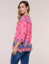 Remera evasé de manga tres cuartos y escote bote, confeccionada en rayón elastizado de color rosado con textura flameada y estampado floral en tonos fucsia y azul.
