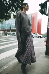 Falda midi de tiro alto ZARA Woman Collection, con diseño evasé y estampado de cuadros en tonos oscuros con líneas rojas y blancas. Cuenta con cierre lateral con cremallera oculta.