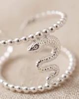 Anillo de acero plateado con diseño de serpiente texturizada y cuerpo de cuentas esféricas, ajustable.