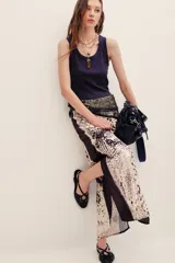 Falda midi fluida con estampado animal print en tonos beige y negro, con detalles de paneles laterales en tela negra y abertura frontal.