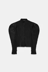 Blusa negra de cuello alto y manga larga abullonada con puños abotonados. Tejido arrugado y cierre frontal oculto con botones. Zara Woman Collection.