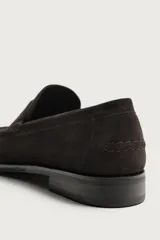 Mocasín de vestir para hombre, fabricado en piel con acabado en serraje de color azul marino. Presenta un diseño clásico con detalle de antifaz en el empeine, horma redonda, costuras visibles en el contorno y una suela sutil con ligero tacón.