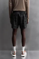 Short deportivo negro con estampado abstracto, cintura elástica ajustable con cordón, bolsillos laterales y trasero con cierre, forro interior y detalle de perforaciones en el ruedo.