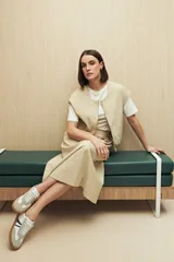 Chaleco color beige sin mangas de silueta relajada, con escote redondeado, cierre frontal con cremallera y ruedo elastizado.