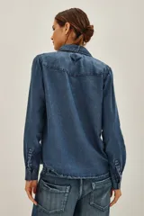Camisa de estilo tejano en color negro lavado, con cuello camisero, cierre frontal con botones metálicos y dos bolsillos delanteros con solapa.
