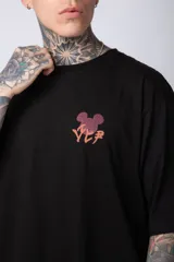 Remera negra de algodón de corte oversize, con mangas cortas y cuello redondo. Estampado pequeño en el frente y diseño grande en la espalda con Mickey Mouse y caracteres orientales en tonos rojizos.