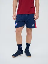 Bermuda deportiva Umbro del Club Nacional de Football, modelo Nexo para hombre, en color azul marino con detalles en rojo y blanco. Cuenta con el escudo del club bordado en la pierna derecha y el logo de Umbro en la izquierda, además de cordón ajustable en la cintura.