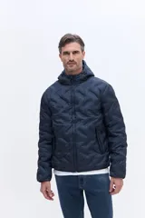 Campera de nylon matelaseada con capucha integrada, cierre frontal y diseño de costuras geométricas. Presenta un ajuste regular y es ideal para climas fríos.