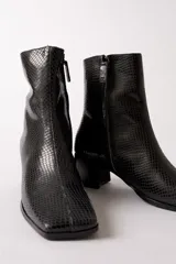 Bota de caña media con textura de reptil en color negro, punta cuadrada y taco bloque.