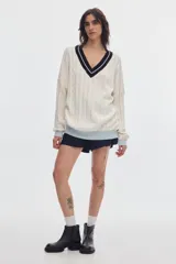 Sweater de punto oversized de color marrón, con escote en V, detalles de ochos y puños, cuello y ruedo en tono celeste y blanco.