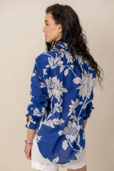 Camisa azul con estampado floral en tono blanco, de manga larga, cuello camisero y cierre frontal de botones.