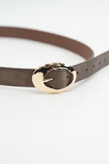 Cinturón de cuero sintético en tono marrón oscuro con acabado texturizado y hebilla ovalada de metal dorado con diseño irregular.