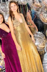 Vestido largo con escote en V, estampado en tonos rojizos y rosados, con un patrón ondulado. Presenta cut-outs laterales bajo el busto y breteles finos que se cruzan en la espalda.