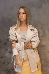 Blazer de corte recto con diseño combinado en brocato y lentejuelas doradas. Presenta mangas con volumen en los hombros y puños largos con recortes geométricos en cuero marrón.