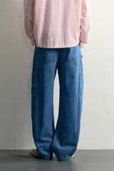 Jeans loose fit de tiro medio, confeccionados en denim de algodón color azul con efecto lavado. Presentan diseño de cinco bolsillos, bolsillo plastrón estilo carpintero en la pierna y cierre frontal con cremallera y botón.