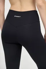 Calza deportiva negra con cintura alta y compresión media. Presenta una franja vertical blanca a lo largo de la pierna.