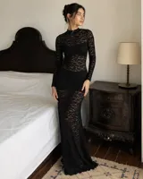 Vestido largo de encaje negro, con cuello alto y mangas largas. Diseño al cuerpo con transparencias.