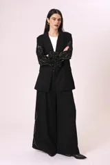 Blazer negro con mangas de encaje bordado y solapas clásicas.