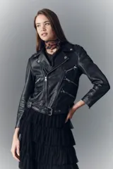 Campera estilo biker confeccionada en cuero ovino, con solapas amplias, charreteras en los hombros y múltiples cierres metálicos frontales. Presenta un diseño ajustado con detalles de herrajes plateados y forro interior de poliéster.