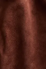 Campera corta marrón de tejido suave con terminación cepillada, cuello camisero, hombros caídos y cierre frontal. Cuenta con bolsillos laterales ribeteados y elástico revestido en puños y dobladillo.