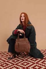 Cartera mochila de diseño versátil, color rosado, confeccionada en material sintético impermeable. Cuenta con doble asa superior, correas ajustables para usar como mochila, compartimento principal con cierre y bolsillo frontal con cierre decorado con tirador largo.