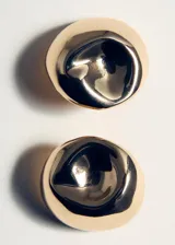 Aros pequeños de diseño redondo con acabado metálico brillante y forma ligeramente abollada.