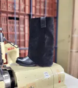 Bota de cuero negro con diseño 2 en 1, que incluye una polaina de gamuza desmontable. Presenta una base de bota de cuero liso y una caña alta de gamuza, ofreciendo versatilidad para diferentes estilos.