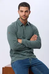 Remera polo de manga larga confeccionada en tejido piqué de algodón. Presenta cuello clásico, cierre frontal con botones y un pequeño aplique decorativo en la manga.