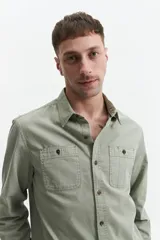 Camisa manga larga color verde oliva, corte slim fit, con cartera abotonada, dos bolsillos frontales con botón y confeccionada en 100% algodón.