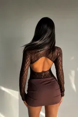 Vestido corto de diseño combinado, con cuerpo de encaje negro de manga larga y falda de ecocuero negro con corte asimétrico y detalle de fruncido lateral.
