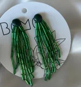 Par de caravanas colgantes con base circular verde oscuro y flecos de canutillos verdes.