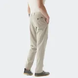 Pantalón chino color beige, de corte recto, con bolsillos laterales y traseros. Se ajusta a la cintura con cinturón de cuero marrón.