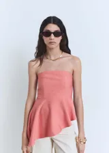 Top strapless color rosado, con diseño entallado y bajo asimétrico con vuelo. Presenta panel fruncido elástico en la parte posterior.